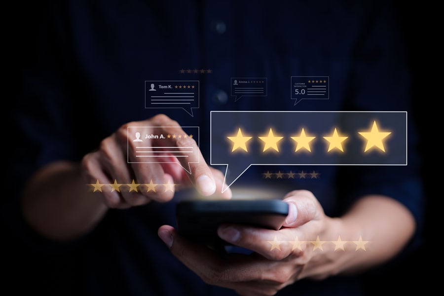 Person tapping cell phone screen with 5 star ratings boxes overlaid